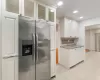 Kitchen with white cabinetry, light stone countertops, stainless steel fridge with ice dispenser, decorative backsplash, and light tile patterned floors