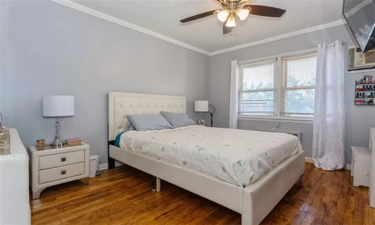 Bedroom featuring dark hardwood / wood-style floors, ceiling fan, and ornamental molding