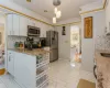 Kitchen with white cabinetry, stainless steel appliances, decorative light fixtures, and ornamental molding