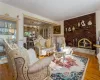 Living room featuring hardwood / wood-style flooring, a chandelier, crown molding, and a brick fireplace