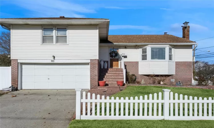 Split level home featuring a garage and a front lawn