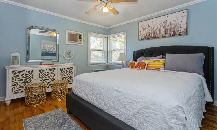 Bedroom featuring a wall mounted AC, ceiling fan, dark hardwood / wood-style floors, and ornamental molding