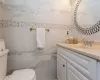 Bathroom featuring vanity, toilet, and tile walls