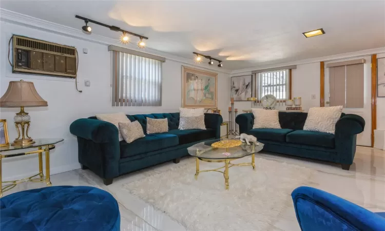 Living room with rail lighting, a wall unit AC, and ornamental molding