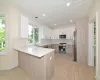 Kitchen featuring sink, stainless steel appliances, tasteful backsplash, kitchen peninsula, and white cabinets