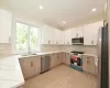 Kitchen with light brown cabinets, sink, decorative backsplash, light stone counters, and stainless steel appliances