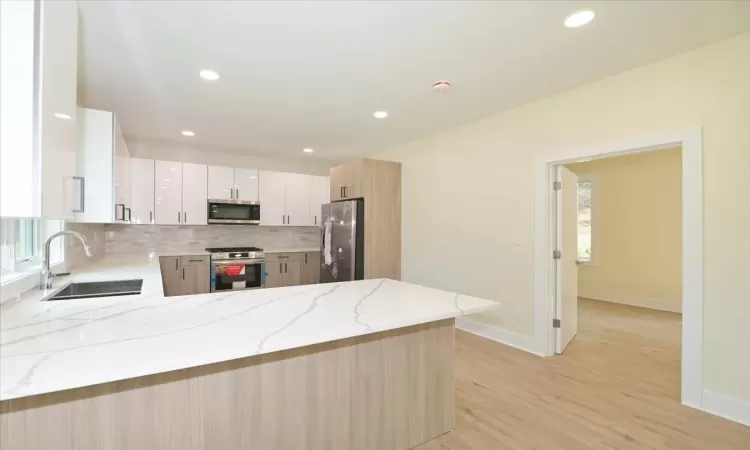 Kitchen with kitchen peninsula, appliances with stainless steel finishes, white cabinets, and sink