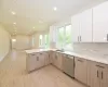 Kitchen with sink, stainless steel dishwasher, light brown cabinetry, tasteful backsplash, and kitchen peninsula