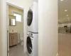 Clothes washing area featuring light tile patterned floors and stacked washer and clothes dryer