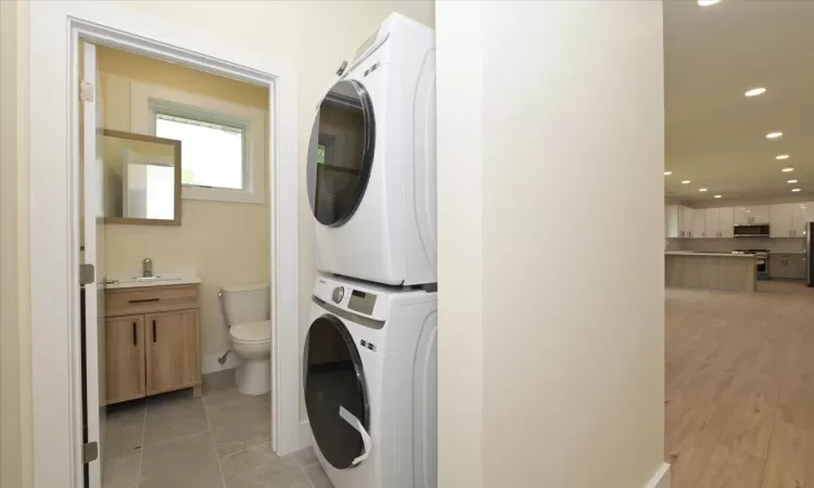 Clothes washing area featuring light tile patterned floors and stacked washer and clothes dryer