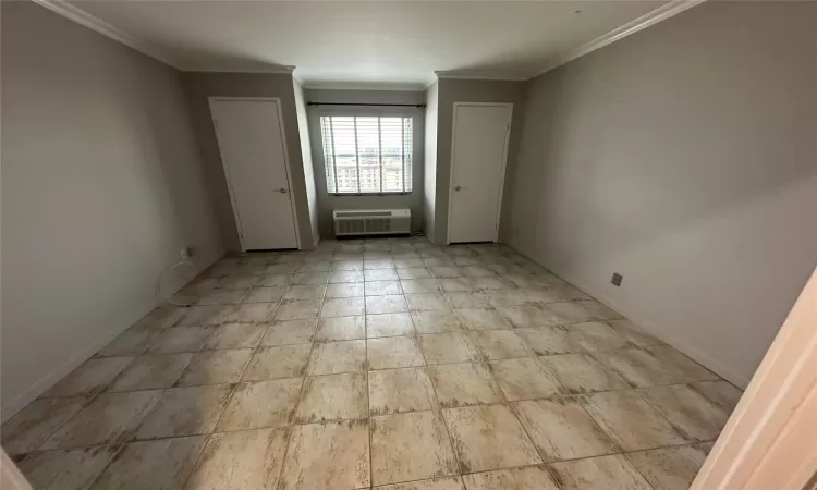 Empty room featuring an AC wall unit and crown molding