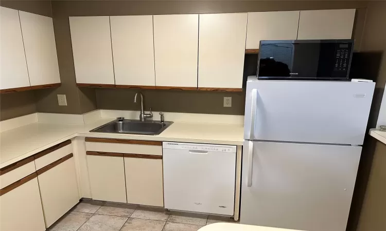 Kitchen with white cabinetry, white appliances, and sink