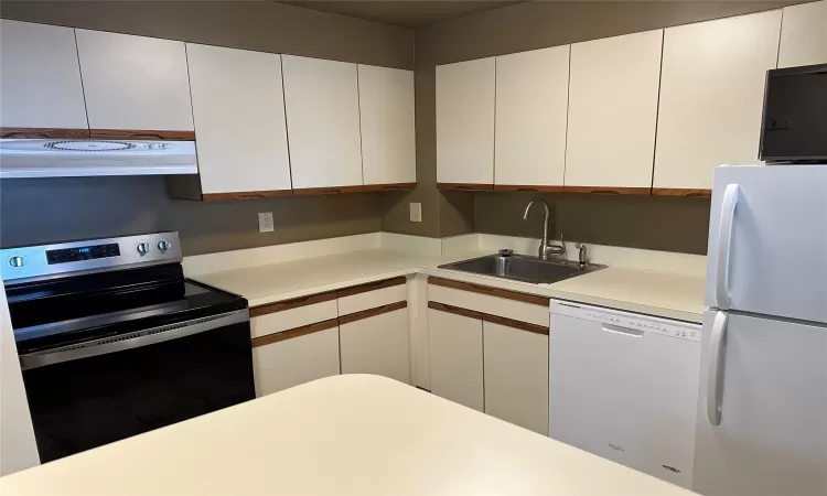 Kitchen with white cabinets, white appliances, ventilation hood, and sink