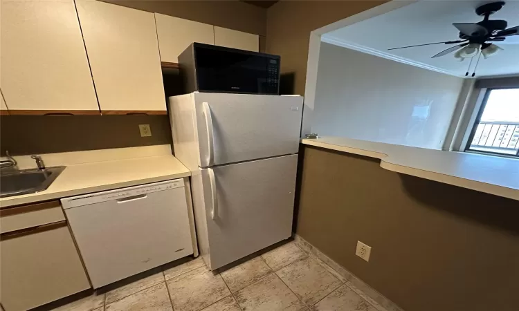 Kitchen with ceiling fan, sink, white appliances, and ornamental molding