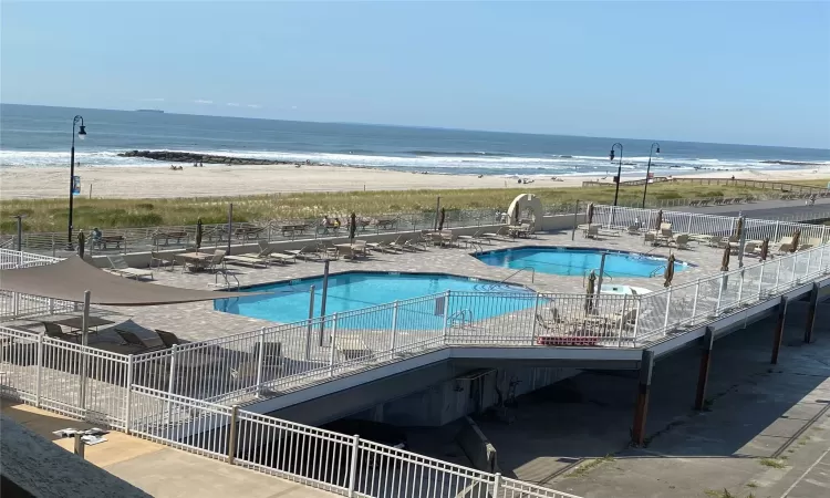 View of pool featuring a view of the beach, a water view, and a patio area