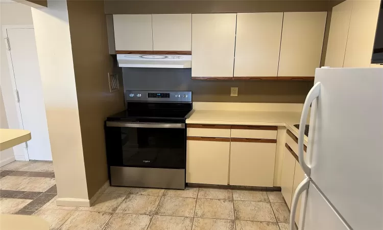 Kitchen featuring white fridge, extractor fan, and stainless steel range with electric stovetop