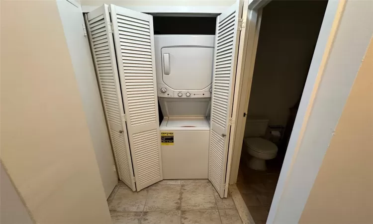 Bathroom with toilet and stacked washer/dryer