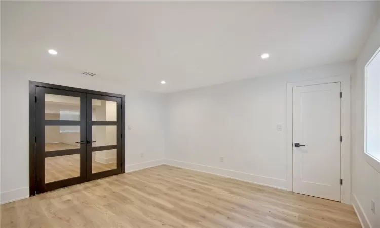 Unfurnished room with light wood-type flooring and french doors