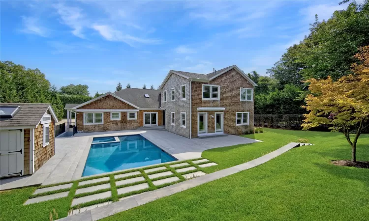 Rear view of property featuring a yard, an outbuilding, and a patio