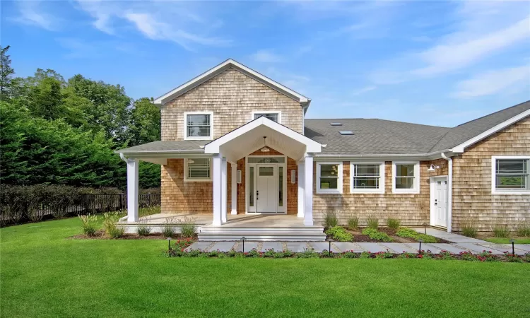 View of front of property with covered porch and a front yard