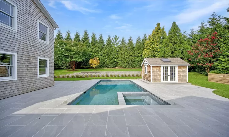 View of pool featuring a patio area, an in ground hot tub, and an outbuilding