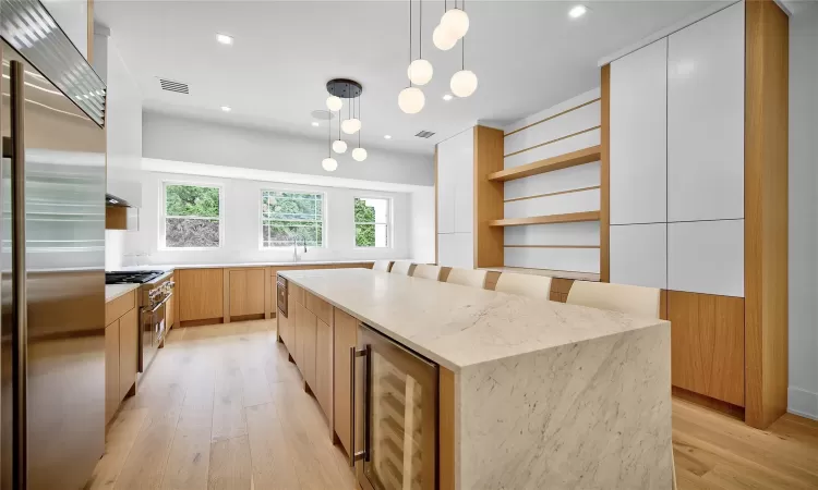 Kitchen with wine cooler, high quality appliances, a center island, white cabinetry, and hanging light fixtures