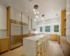 Kitchen featuring light wood-type flooring, white cabinets, a center island, hanging light fixtures, and built in fridge