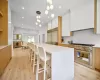 Kitchen with high end appliances, a center island, decorative light fixtures, white cabinets, and light wood-type flooring