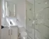 Bathroom with vanity, toilet, and a shower with door