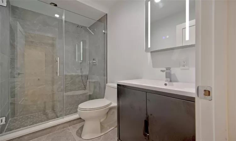 Bathroom featuring tile patterned floors, vanity, walk in shower, and toilet