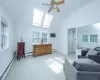 Sitting room with carpet, lofted ceiling with skylight, ceiling fan, baseboard heating, and a wall mounted AC