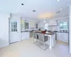 Kitchen with premium range hood, white cabinets, decorative light fixtures, and appliances with stainless steel finishes