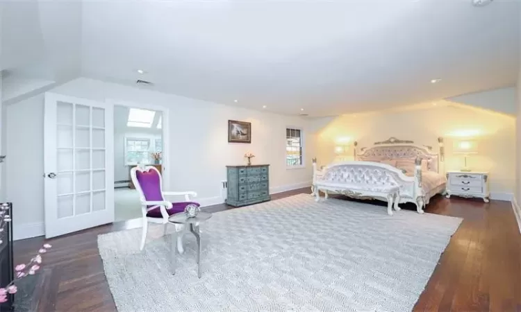 Bedroom with dark hardwood / wood-style floors, multiple windows, and a baseboard heating unit