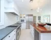 Kitchen with ornamental molding, beverage cooler, built in appliances, decorative light fixtures, and white cabinets