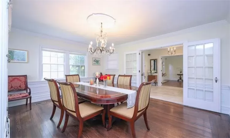 Dining area featuring dark hardwood / wood-style flooring, ornamental molding, french doors, and a chandelier