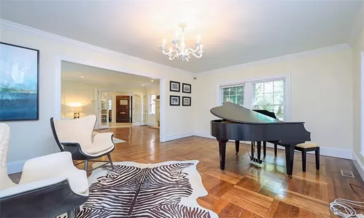 Sitting room with crown molding, parquet floors, and a notable chandelier