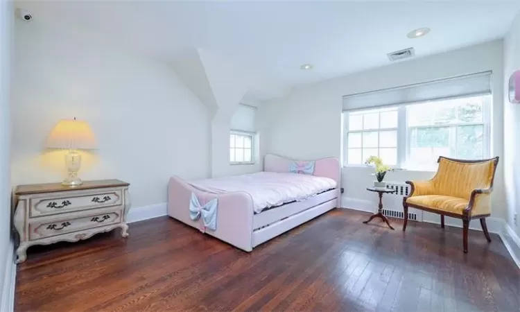 Bedroom with dark hardwood / wood-style flooring, radiator heating unit, and vaulted ceiling