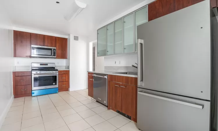 Kitchen with light tile patterned floors, stainless steel appliances, and sink