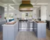 Kitchen with stainless steel range with gas cooktop, a kitchen island, a healthy amount of sunlight, custom range hood, and beverage cooler