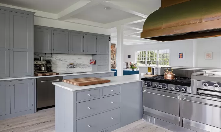 Kitchen with stainless steel appliances, tasteful backsplash, light hardwood / wood-style flooring, beamed ceiling, and custom range hood