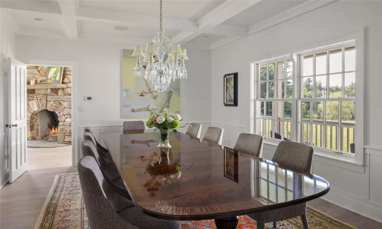 Dining space with beamed ceiling, a stone fireplace, plenty of natural light, and coffered ceiling