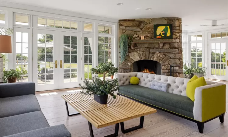 Sunroom featuring a fireplace, french doors, plenty of natural light, and ceiling fan