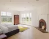 Bedroom featuring light hardwood / wood-style floors, crown molding, access to outside, and a brick fireplace