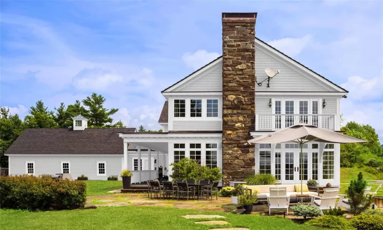 Rear view of property with a lawn, a patio area, french doors, and a balcony