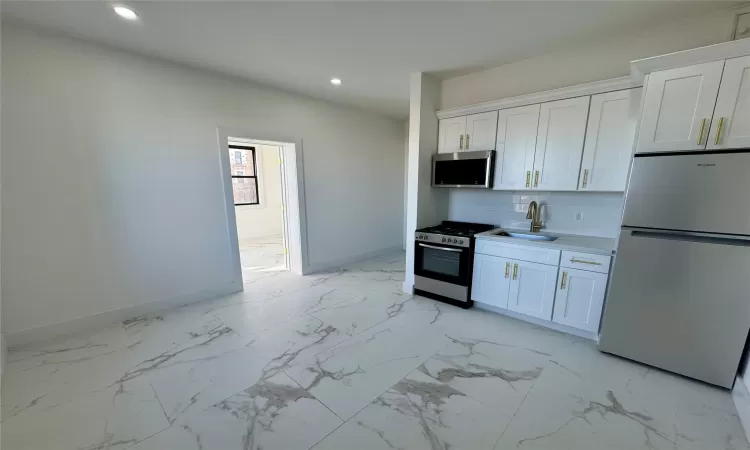 Kitchen featuring appliances with stainless steel finishes, backsplash, white cabinetry, and sink