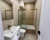 Full bathroom with bath / shower combo with glass door, vanity, tile walls, tile patterned flooring, and toilet