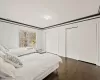 Bedroom with ornamental molding, dark wood-type flooring, a baseboard radiator, and two closets