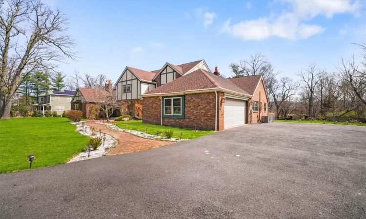 View of front of house featuring a garage, central air condition unit, and a front lawn