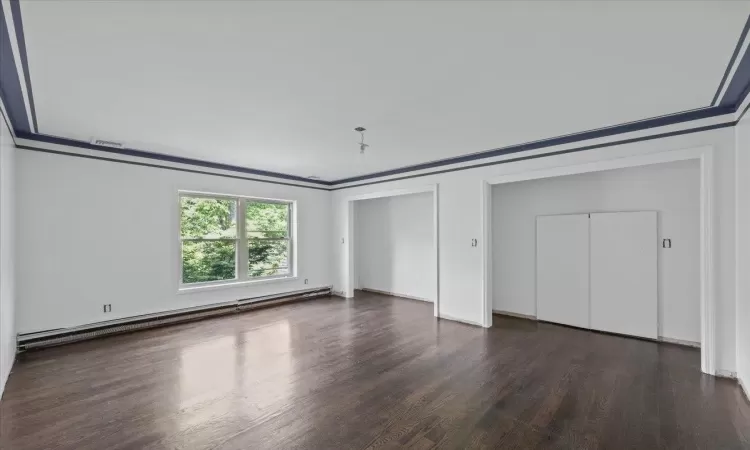 Unfurnished bedroom with dark hardwood / wood-style floors, ornamental molding, and a baseboard radiator