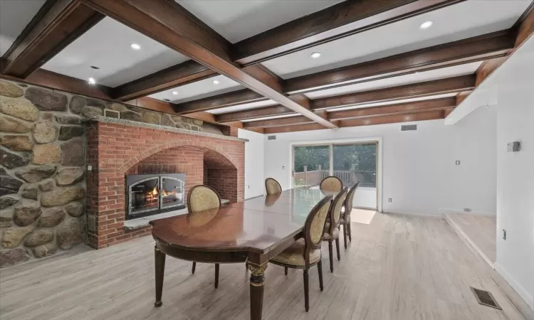 Dining room featuring a fireplace, beamed ceiling, and light hardwood / wood-style floors